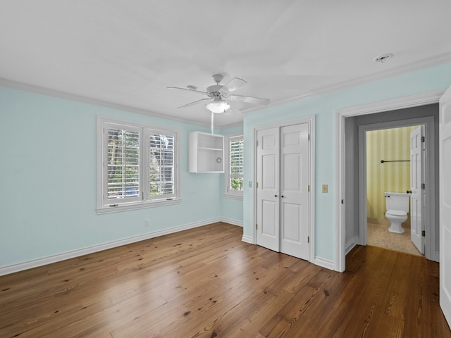 unfurnished bedroom featuring crown molding, ceiling fan, wood-type flooring, and a closet