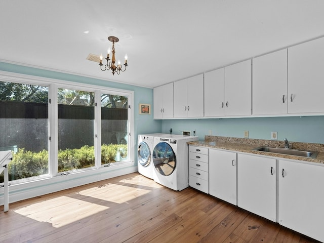 washroom with sink, a chandelier, cabinets, washing machine and clothes dryer, and light hardwood / wood-style flooring