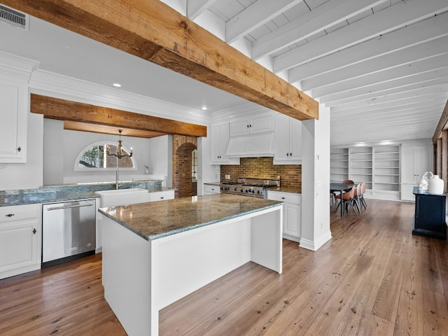 kitchen with sink, premium range hood, stainless steel appliances, white cabinets, and a kitchen island