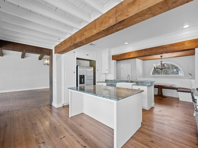 kitchen with sink, white cabinetry, a kitchen island, beamed ceiling, and stainless steel appliances