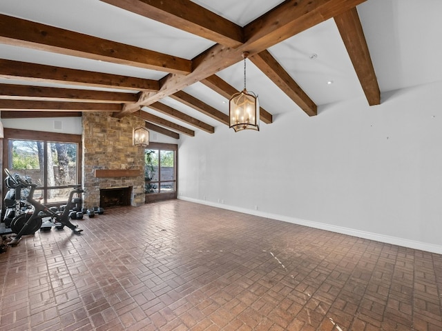 unfurnished living room with a stone fireplace, vaulted ceiling with beams, and an inviting chandelier