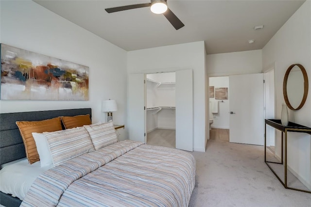 bedroom featuring a spacious closet, light carpet, ceiling fan, and a closet