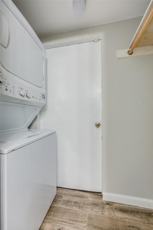 clothes washing area with stacked washer / dryer and light hardwood / wood-style flooring