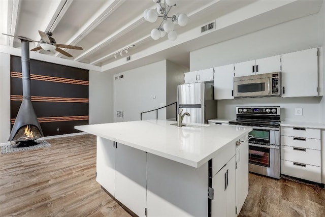 kitchen with hardwood / wood-style floors, an island with sink, white cabinetry, sink, and stainless steel appliances