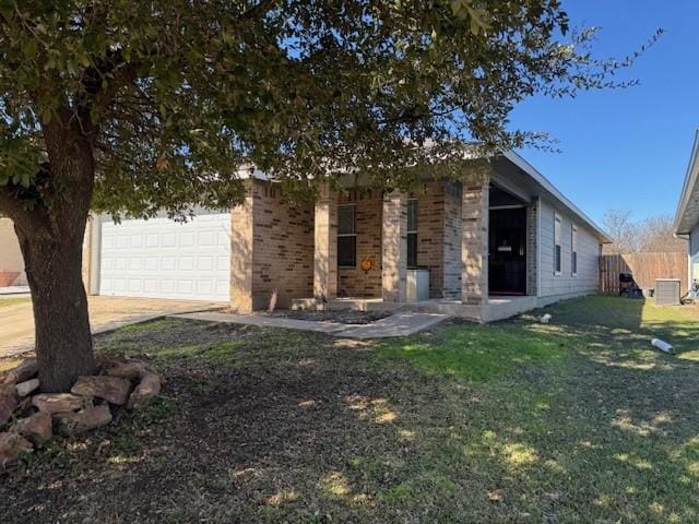 view of front of property featuring brick siding, fence, a front yard, a garage, and driveway