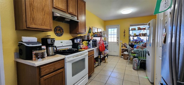 kitchen featuring light tile patterned floors, stainless steel fridge, and white range with electric cooktop