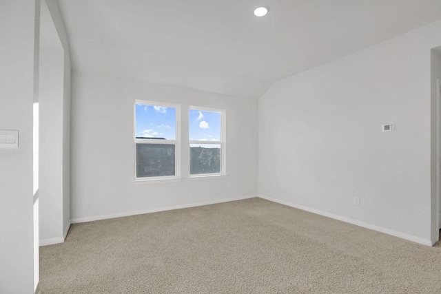 unfurnished room featuring lofted ceiling and light colored carpet