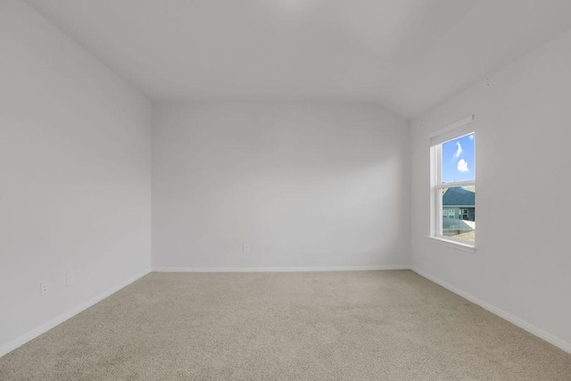 carpeted empty room with lofted ceiling