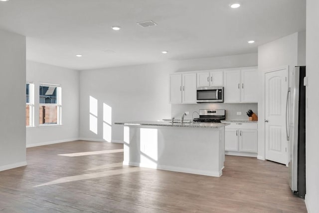 kitchen featuring white cabinetry, backsplash, an island with sink, and appliances with stainless steel finishes