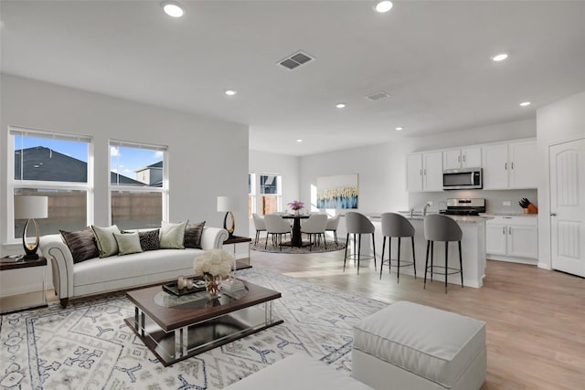 living room featuring sink and light hardwood / wood-style floors