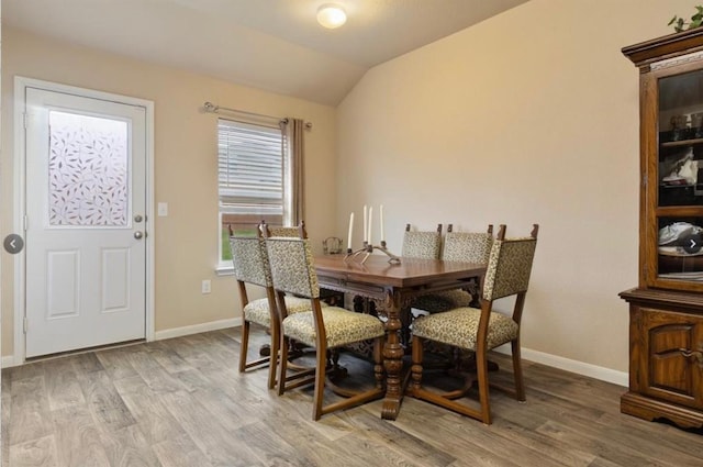 dining space featuring vaulted ceiling and light wood-type flooring