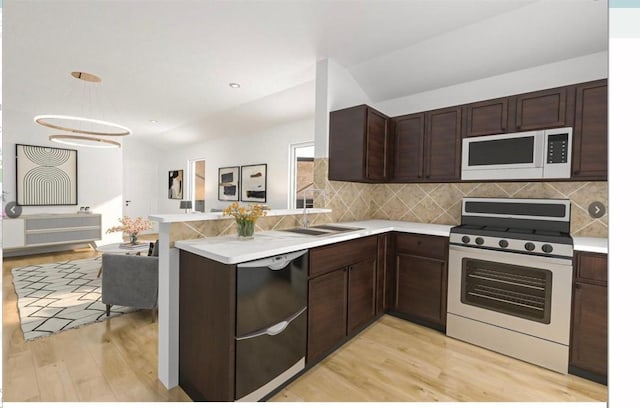 kitchen with lofted ceiling, sink, hanging light fixtures, stainless steel range, and kitchen peninsula