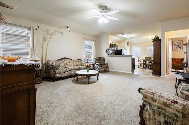 carpeted living room with ceiling fan and vaulted ceiling