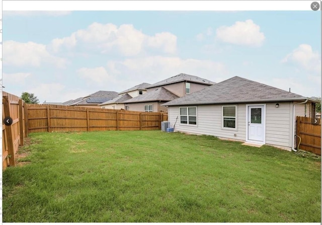 rear view of house featuring cooling unit and a lawn