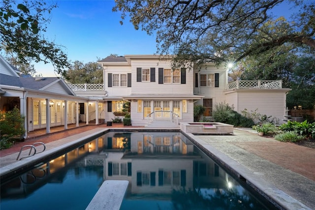 back of property featuring a pool with hot tub and a patio