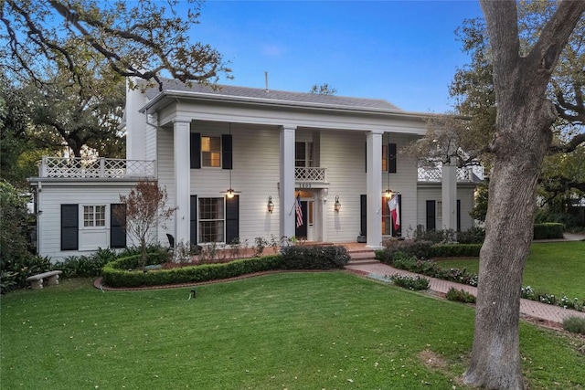 greek revival inspired property with a front yard and a balcony