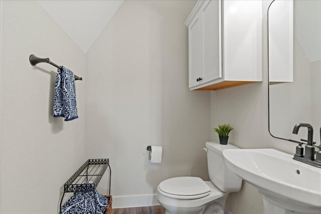 bathroom with wood-type flooring, lofted ceiling, sink, and toilet