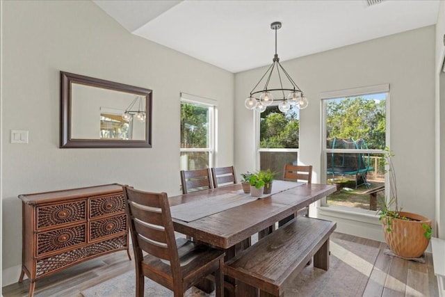 dining space with hardwood / wood-style floors and a notable chandelier