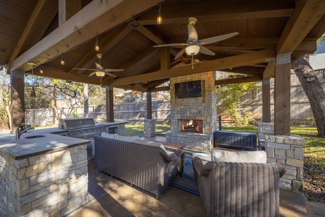 view of patio / terrace with sink, a gazebo, an outdoor living space with a fireplace, grilling area, and an outdoor kitchen