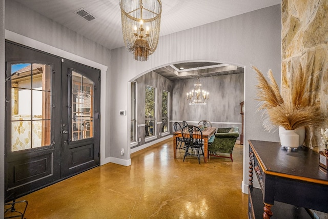 foyer featuring an inviting chandelier, concrete flooring, and french doors