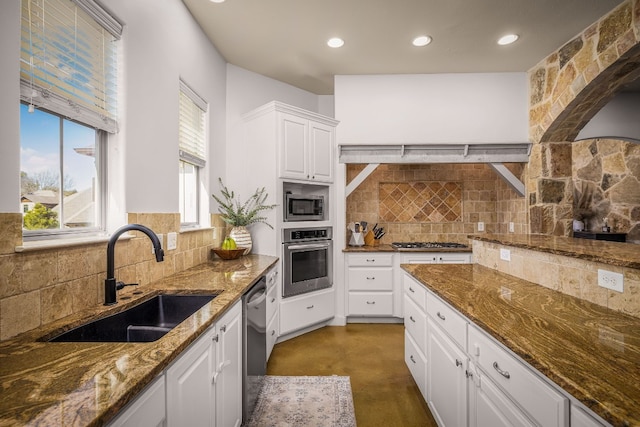 kitchen featuring white cabinetry, stainless steel appliances, sink, and dark stone counters