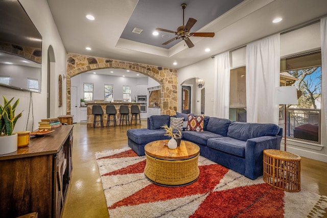 living room with a tray ceiling and ceiling fan