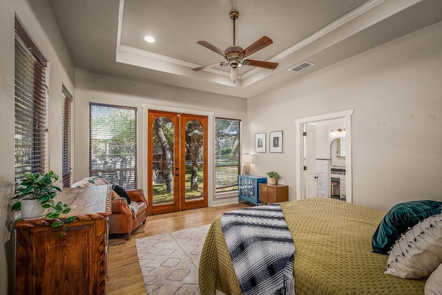 bedroom featuring multiple windows, a tray ceiling, and french doors