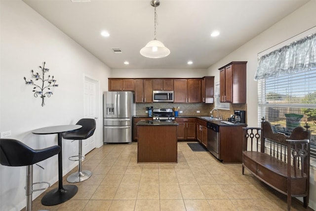 kitchen with a kitchen island, appliances with stainless steel finishes, sink, decorative backsplash, and hanging light fixtures