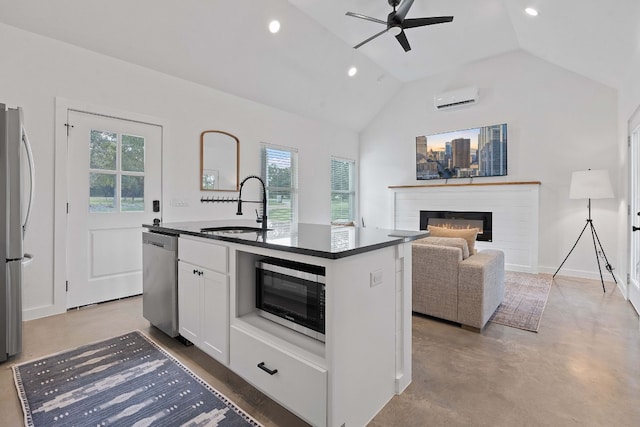 kitchen featuring appliances with stainless steel finishes, an AC wall unit, an island with sink, sink, and white cabinets