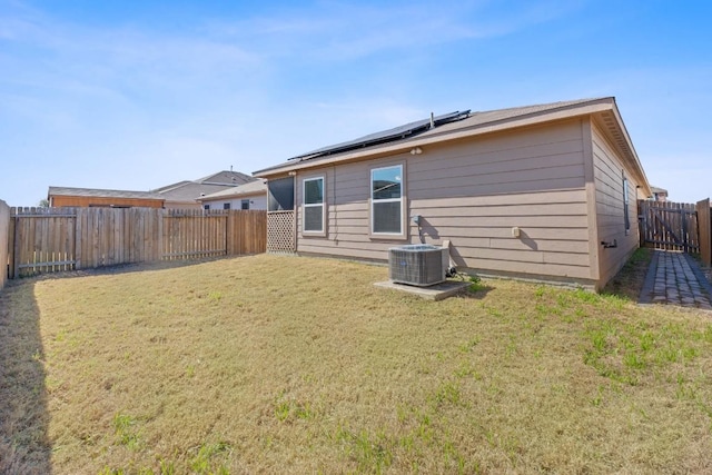 back of house with cooling unit, a yard, and solar panels