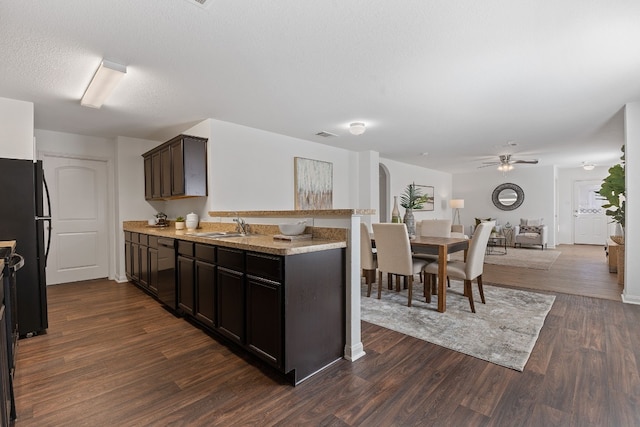 kitchen with sink, dark hardwood / wood-style floors, dark brown cabinetry, black appliances, and a textured ceiling