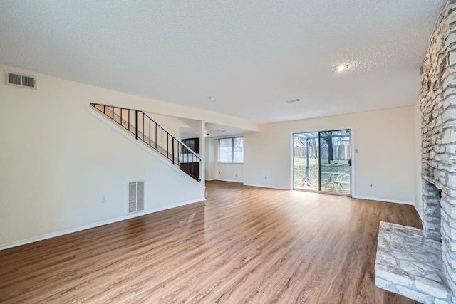 unfurnished living room featuring a fireplace, light hardwood / wood-style flooring, and a textured ceiling