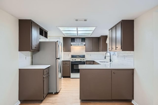 kitchen featuring sink, decorative backsplash, stainless steel refrigerator, and white gas range oven