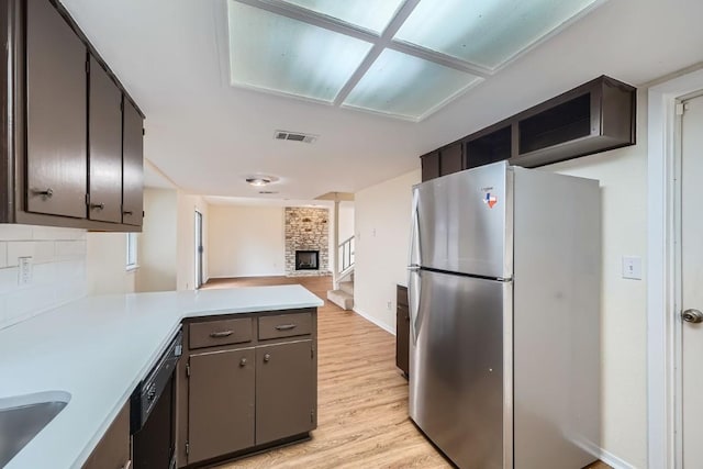 kitchen with stainless steel refrigerator, dishwasher, backsplash, kitchen peninsula, and light wood-type flooring