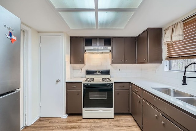 kitchen featuring sink, tasteful backsplash, light hardwood / wood-style flooring, stainless steel fridge, and white range with gas cooktop