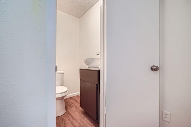 bathroom with vanity, toilet, hardwood / wood-style floors, and a textured ceiling