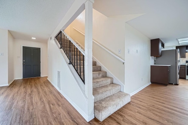 stairway with wood-type flooring and a textured ceiling