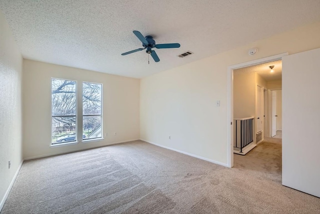 carpeted spare room featuring ceiling fan and a textured ceiling