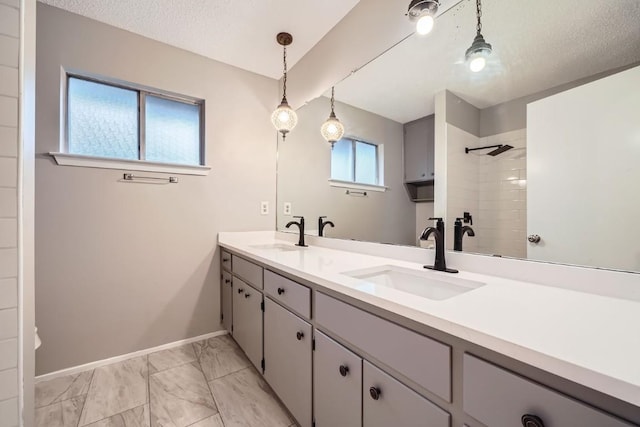 bathroom with vanity, a tile shower, and a textured ceiling