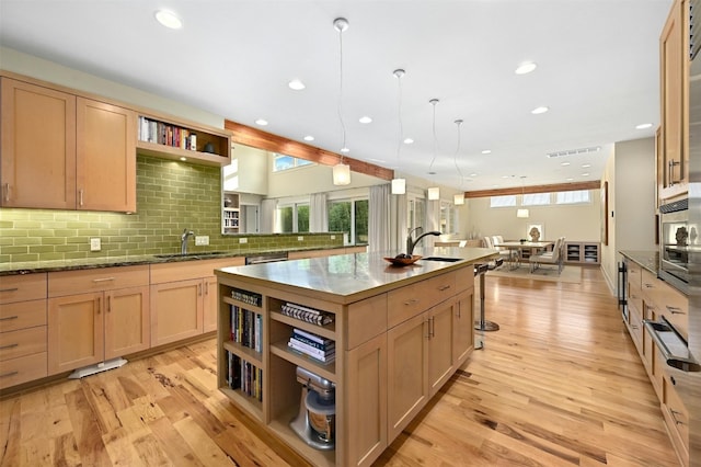 kitchen featuring pendant lighting, sink, light brown cabinets, and a center island with sink