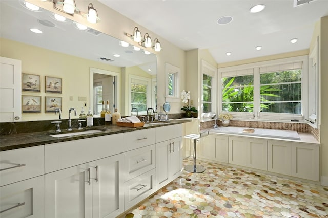 bathroom featuring vanity, vaulted ceiling, and a tub