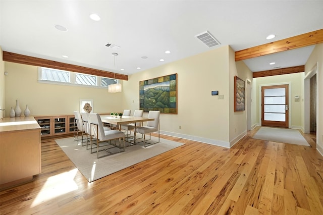 dining space with beam ceiling and light wood-type flooring