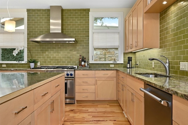 kitchen featuring sink, light brown cabinets, appliances with stainless steel finishes, light stone countertops, and wall chimney range hood