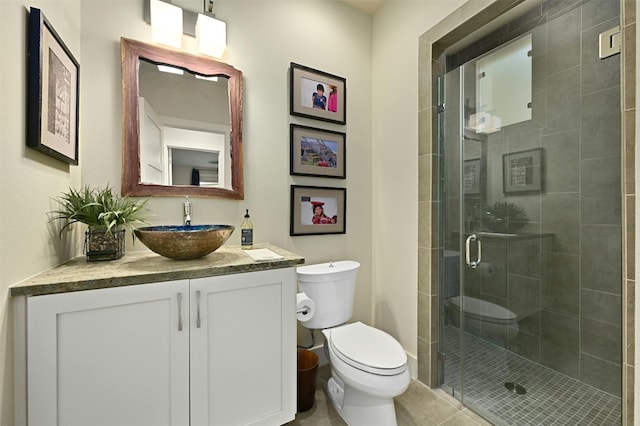 bathroom featuring a shower with door, vanity, tile patterned floors, and toilet