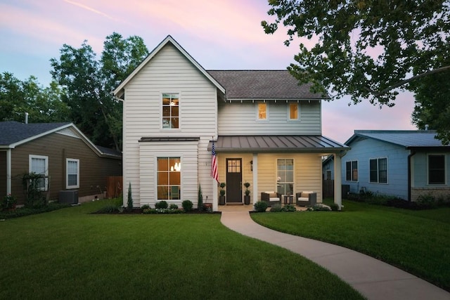 view of front facade with metal roof, a porch, central AC, a yard, and a standing seam roof