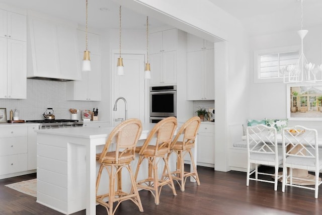 kitchen with tasteful backsplash, breakfast area, dark wood-type flooring, stainless steel appliances, and a kitchen bar