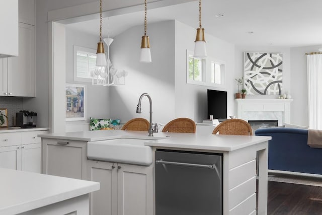 kitchen featuring light countertops, a premium fireplace, a sink, and dark wood finished floors