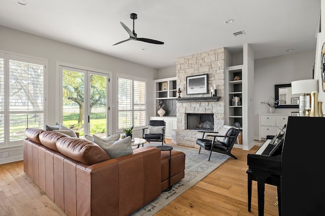 living room with ceiling fan, a wealth of natural light, a fireplace, and light hardwood / wood-style flooring