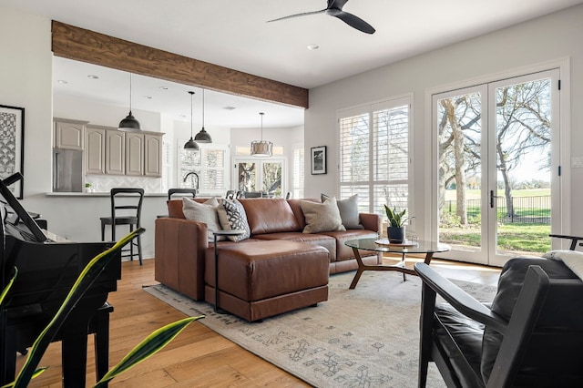 living room featuring beamed ceiling, ceiling fan, light wood-type flooring, and french doors