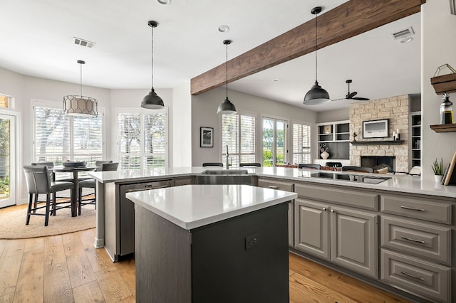 kitchen featuring a kitchen island, pendant lighting, beamed ceiling, gray cabinetry, and light hardwood / wood-style flooring